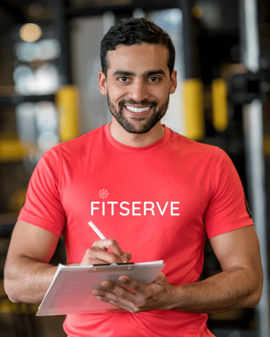 Fitserve coach reviewing a client's training plan on a clipboard inside a modern Mumbai gym